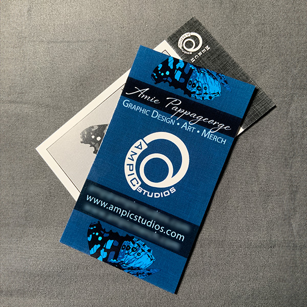 A vertical business card with a navy blue front and grayscale art back.